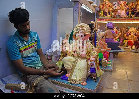 Un artiste décore l'idole du Dieu hindou à tête d'éléphant Ganesh pour la vente dans un atelier. Les artisans obtiennent les idoles du Dieu hindou à tête d'éléphant Ganesh prêtes à la vente car le festival de dix jours de Ganesh Chaturthi commencera du 27 août au 6 septembre qui sera célébré dans tout le pays. Banque D'Images