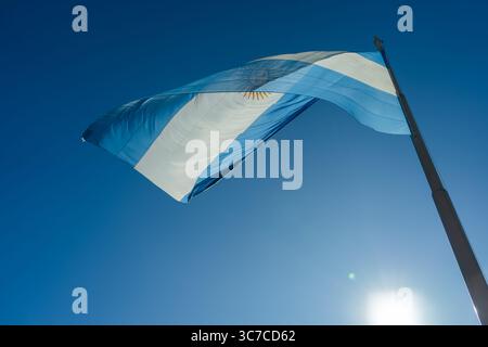Le drapeau national de l'argentine agitant fièrement contre un ciel bleu clair, illuminé par la lumière du soleil Banque D'Images