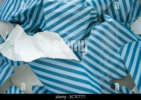 Papier d'emballage rayé déchiré en gros plan, symbole des déchets saisonniers et de l'utilisation excessive de papier Banque D'Images