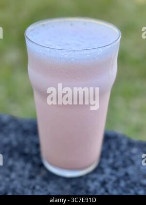 Boisson rafraîchissante à la pastèque avec de la glace et de l'eau tonique servie dans un verre sur une table de basalte en plein air. Banque D'Images