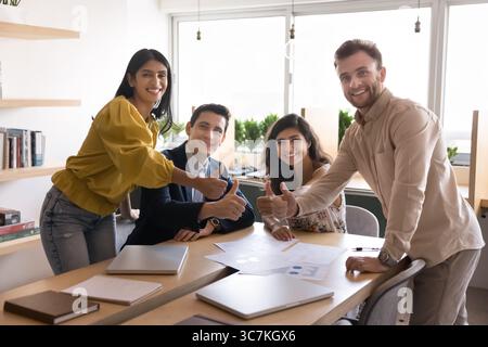 Équipe d'affaires diversifiée montrant le pouce vers le haut avec une expression joyeuse Banque D'Images