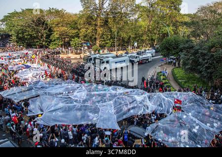9 février 2021, Yangon, Myanmar : les manifestants se couvrent de bâches en plastique alors que les forces de police les avertissent de se disperser ou de se faire arroser d’eau à Hledan lors du quatrième jour de manifestations contre le coup d’État militaire..des milliers de personnes sont descendues dans les rues de Yangon le quatrième jour de manifestation contre le coup d’État militaire et ont exigé la libération d’Aung San Suu Kyi. L'armée du Myanmar a arrêté la conseillère d'État du Myanmar Aung San Suu Kyi le 1er février 2021 et a déclaré l'état d'urgence tout en prenant le pouvoir dans le pays pendant un an après avoir perdu l'élection contre le l national Banque D'Images