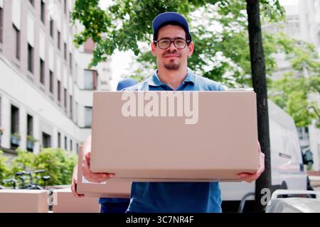 Déménageurs certifiés déchargeant des boîtes dans le service de livraison efficace pour la relocalisation. Banque D'Images