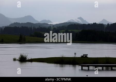 02 août 2025, Bavière, Roßhaupten : le lac Illasberg au bord des Alpes se trouve sous la pluie tôt le matin. Photo : Karl-Josef Hildenbrand/dpa Banque D'Images