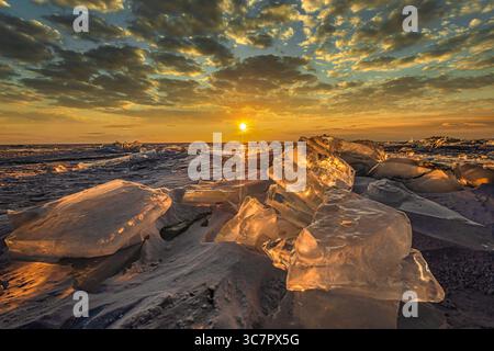 Coucher de soleil reflété dans un grand bloc de glace hummock sur l'arrière-plan du lac gelé. Banque D'Images