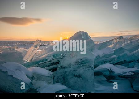 Coucher de soleil reflété dans un grand bloc de glace hummock sur l'arrière-plan du lac gelé. Banque D'Images