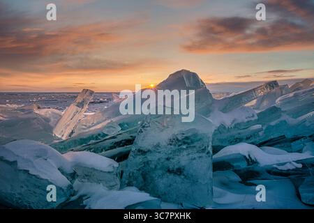 Coucher de soleil reflété dans un grand bloc de glace hummock sur l'arrière-plan du lac gelé. Banque D'Images