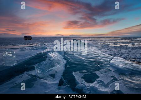 Coucher de soleil reflété dans un grand bloc de glace hummock sur l'arrière-plan du lac gelé. Banque D'Images
