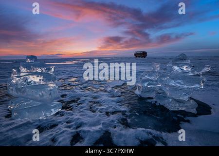 Coucher de soleil reflété dans un grand bloc de glace hummock sur l'arrière-plan du lac gelé. Banque D'Images