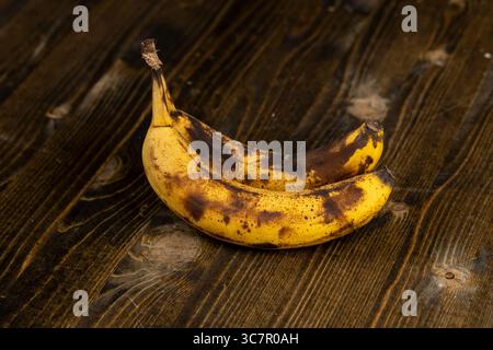 banane noircie pendant le stockage sur un tableau noir, banane pourrie noircie sur une table en bois Banque D'Images