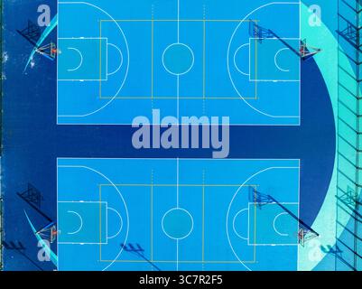 Vue aérienne de dessus des terrains de basket-ball bleu éclatant dans un complexe sportif urbain en plein air avec disposition symétrique et motifs géométriques Banque D'Images