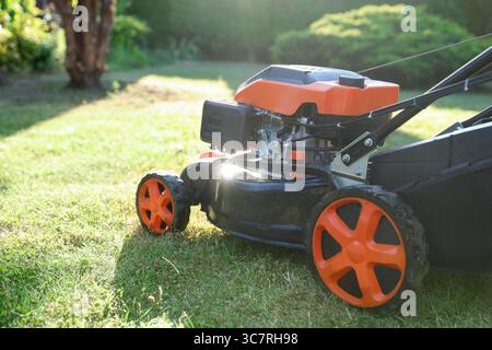 Une tondeuse à gazon sur l'herbe verte dans le jardin, gros plan. Espace pour le texte Banque D'Images