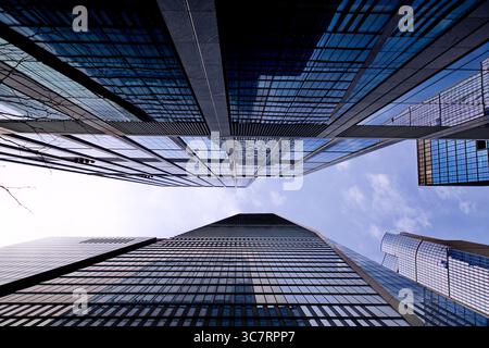 Une vue dynamique vers le ciel des imposantes flèches de verre d'une rue animée de Manhattan à New York révèle une géométrie étincelante et une échelle urbaine spectaculaire. Banque D'Images