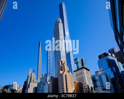 La Steinway Tower et le 432 Park Avenue s’élèvent derrière des gratte-ciel historiques de Billionaires’ Row à Manhattan, formant un amas scintillant contre un ciel bleu. Banque D'Images