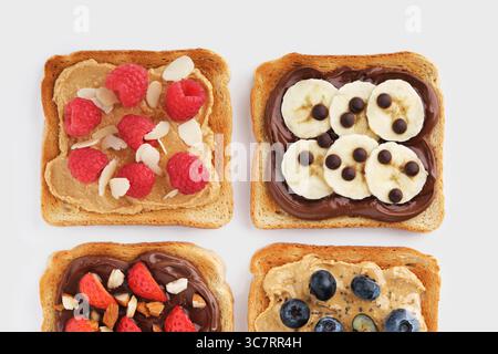 Toasts sucrés aux framboises, banane, fraises, bleuets sur fond clair. À plat. Banque D'Images
