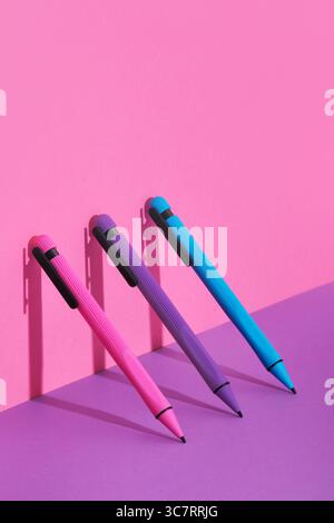 Set de papeterie avec des stylos magenta, cyan et violet vif se dressent sur fond rose et violet. Copyspace. Banque D'Images