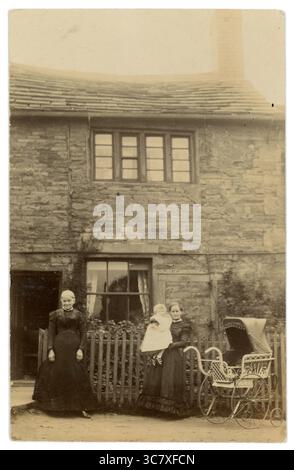 Carte postale de l'ère victorienne originale d'une grand-mère avec une mère et un bébé avec une poussette élaborée, debout à l'extérieur de leur maison victorienne / chalet de campagne. Circa 1902. ROYAUME-UNI Banque D'Images
