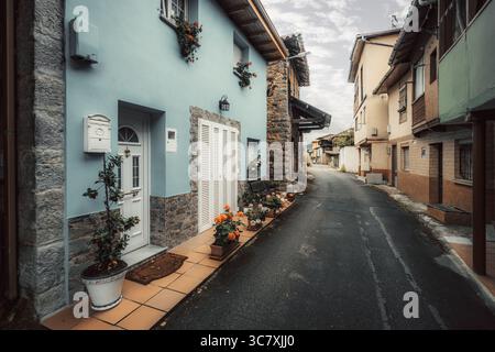 Pittoresque rue étroite dans un petit village asturien, avec des façades colorées, des fleurs en pot, des détails en pierre, et des entrées confortables créant un charmant an Banque D'Images
