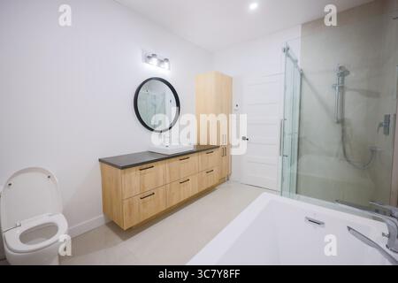 Une salle de bains propre et bien éclairée dans une maison, avec des luminaires modernes et un design minimaliste. Banque D'Images