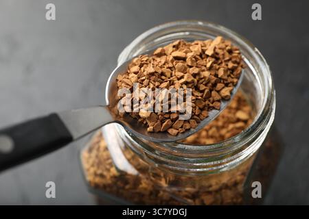 Cuillère avec café instantané granulé et pot sur la table sombre, gros plan Banque D'Images