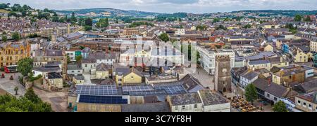 Perspective drone de la tour de l’horloge de St Leonard dans le centre du marché de Newton Abbot, montrant la tour de pierre gothique, les cadrans d’horloge, les boutiques et la zone piétonne – un co Banque D'Images