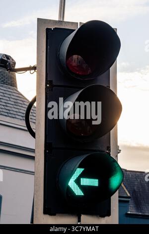 Une flèche verte de virage à gauche sur un feu de circulation indique la direction sécuritaire pour les véhicules à suivre Banque D'Images