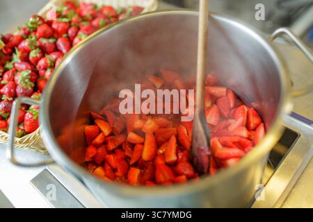 Fraises fraîches bouillant à la vapeur dans un pot en métal pour la préparation du dessert ou de la confiture dans la cuisine gros plan Banque D'Images
