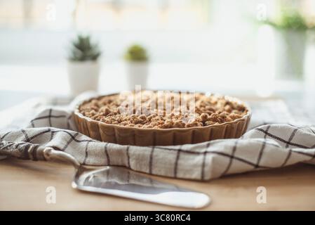 Gros plan d'un gâteau crumble aux myrtilles sur une table en bois avec un serveur à gâteau et un torchon Banque D'Images