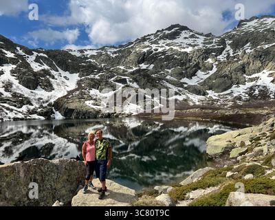Couple debout sur un rocher au bord d'un lac alpin, les bras autour l'un de l'autre, Zakopane, Pologne Banque D'Images