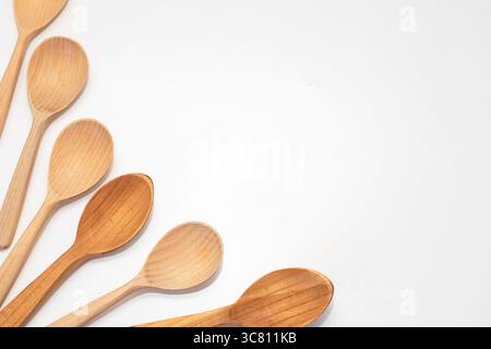Cinq cuillères en bois disposées sur un fond blanc. Ustensiles de cuisine naturels rustiques pour cuisiner, servir et style de vie respectueux de l'environnement. Banque D'Images