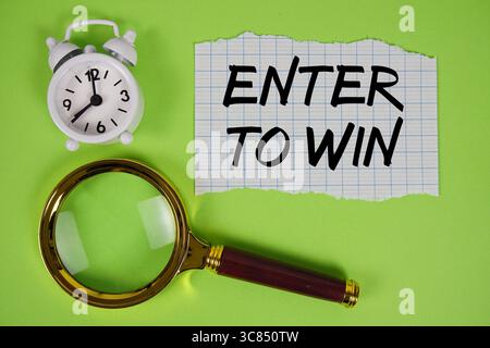 Entrez pour gagner texte écrit sur papier avec loupe et réveil Banque D'Images