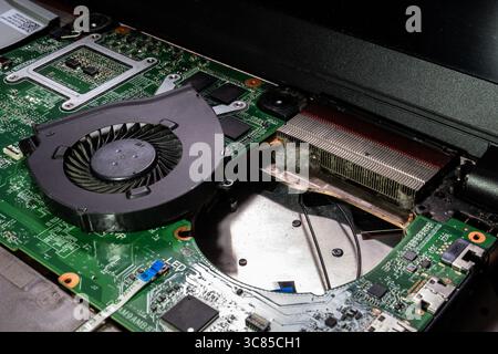 Gros plan du système de refroidissement d'ordinateur portable poussiéreux avec dissipateurs thermiques, ventilateur et carte de circuit imprimé nécessitant un nettoyage Banque D'Images