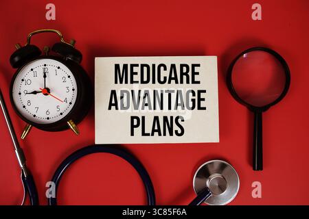 Medicare Advantage plans texte écrit sur carte papier avec stéthoscope, réveil et loupe sur fond rouge Banque D'Images