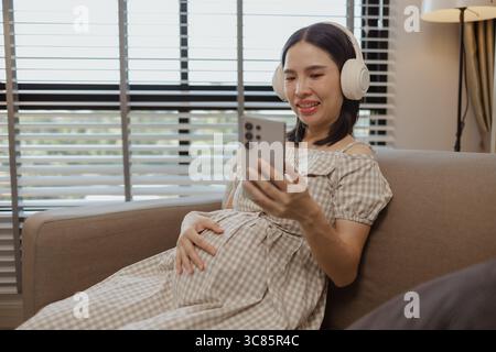 une mère enceinte se détache sur un canapé dans sa propre maison, la grossesse d'une femme, la famille, une femme était très heureuse parce qu'elle était enceinte et allait bientôt g Banque D'Images