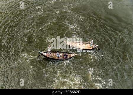 Vue aérienne de deux bateaux à rames traditionnels en bois avec des populations locales, naviguant dans les eaux calmes brunes de la rivière dans une zone rurale du Bangladesh. Banque D'Images