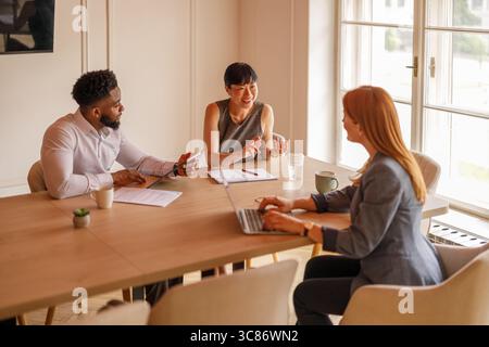 Des collègues professionnels heureux examinant les données et échangeant des idées lors de discussions d'équipe en salle de conseil Banque D'Images