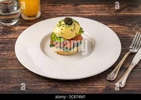 Oeufs gourmands benedict avec saumon fumé et caviar sur assiette blanche Banque D'Images
