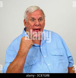 Homme plus âgé portant une chemise à carreaux bleue et blanche acclamant et pompant le poing fermé Banque D'Images