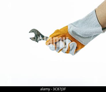 Une main gantée en cuir saisit fermement la clé réglable sur fond blanc Uni, montrant un sentiment de disponibilité et de précision Banque D'Images