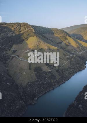 Vue aérienne de la spectaculaire rivière Sil sculpte à travers des collines escarpées et en terrasses sous un ciel doux, Ribeira Sacra, Lugo, Espagne. Banque D'Images