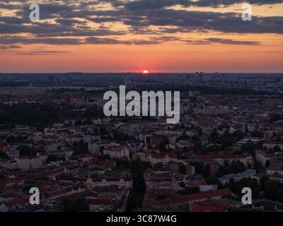 Vue aérienne du coucher de soleil sur le paysage urbain, projetant une lueur chaude sur les bâtiments de Neukölln, créant un beau contraste avec le ciel sombre, Berlin, Allemagne. Banque D'Images