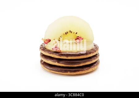 Biscuits au chocolat nappés de kiwis tranchés et de pétales de rose comestibles Banque D'Images