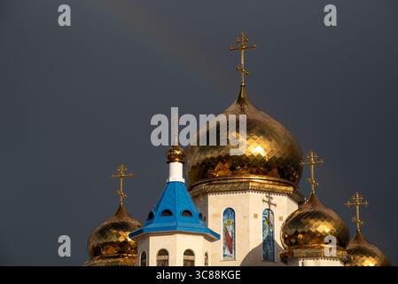 Les dômes dorés et les croix d'une église orthodoxe brillent brillamment contre un ciel orageux Banque D'Images