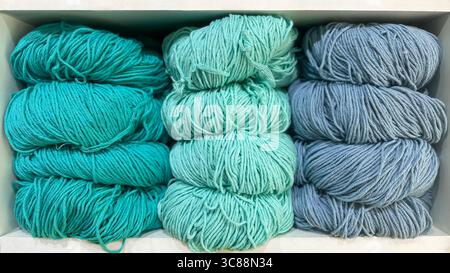 assortiment vibrant de laine, de mélange de laine et de fils de coton de différentes couleurs soigneusement disposés sur des étagères blanches propres Banque D'Images