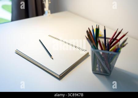 carnet de croquis illuminé par lampe et jeu de crayons de couleur sur table, dessin et passe-temps, concept de retour à l'école Banque D'Images
