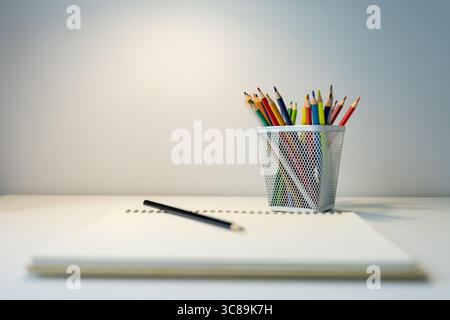carnet de croquis illuminé par lampe et jeu de crayons de couleur sur table, dessin et passe-temps, concept de retour à l'école Banque D'Images
