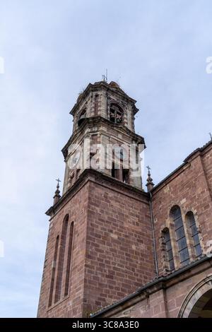 Une vue en bas angle capture les détails architecturaux d'une tour d'église historique en briques sous un ciel nuageux, mettant en valeur son design intemporel. Banque D'Images