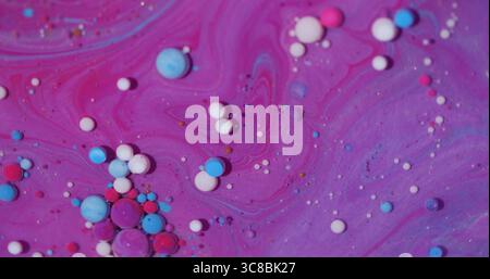 Particules d'encre. Peinture à l'eau. Défocalisé des gouttelettes colorées bleu rose scintillant huile liquide violet blanc flottant sur fond d'art abstrait. Banque D'Images