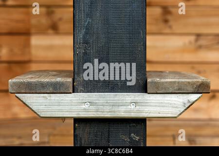 Une étagère en bois est solidement fixée à un pilier noir à l'intérieur d'une cabine confortable, mettant en valeur des éléments de design rustique et des matériaux naturels. Banque D'Images