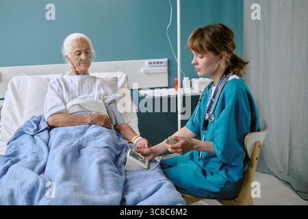 Infirmière caucasienne mesurant la pression artérielle d'une femme caucasienne senior Banque D'Images